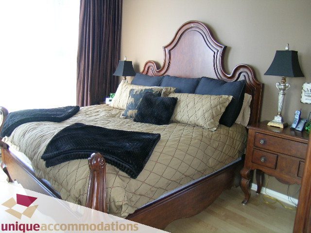 Spacious bedroom with a large bed, wooden headboard, and neatly arranged bedding. - 3601-193 Aquarius Mews, Vancouver Downtown