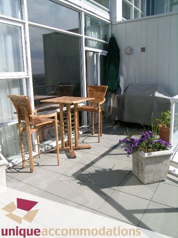 Furnished patio with outdoor furniture, potted plants, and city view. - 3601-193 Aquarius Mews, Vancouver Downtown
