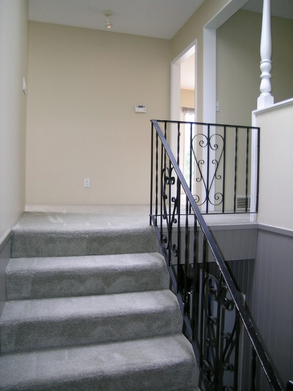 Staircase leading to upper level with wrought iron railing and carpeted steps. - 2331 Hyannis Drive, North Vancouver