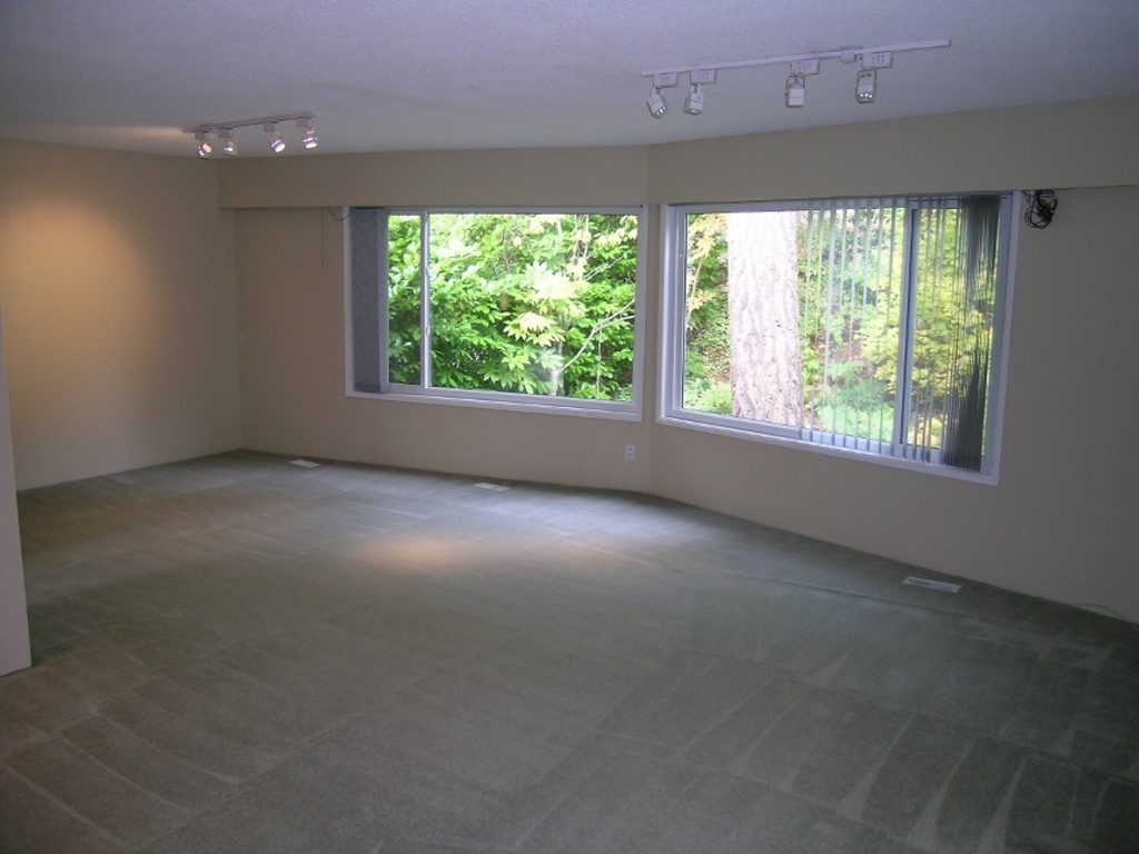 Spacious living room with large windows and stone flooring, perfect for relaxation. - 2331 Hyannis Drive, North Vancouver