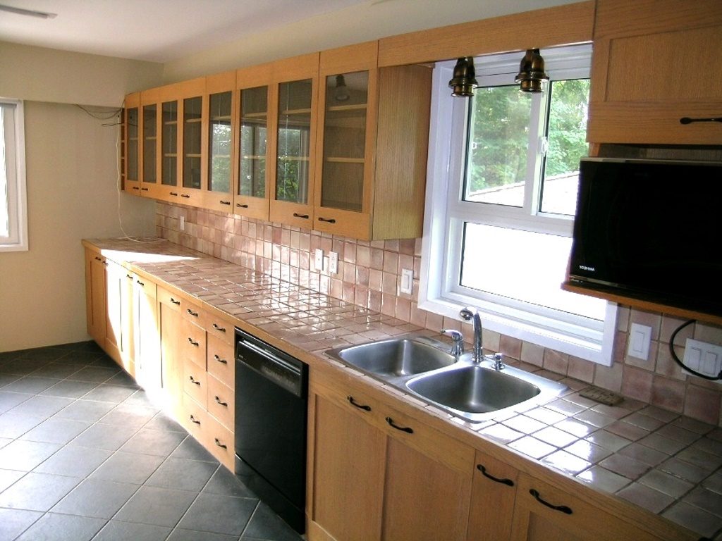 Bright kitchen with light wood cabinets, tiled countertops, and a large window. - 2331 Hyannis Drive, North Vancouver