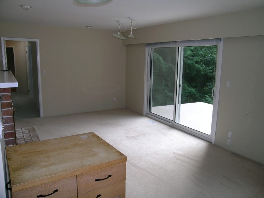 Spacious living room with hardwood floors, large windows, and a view of greenery. - 2331 Hyannis Drive, North Vancouver