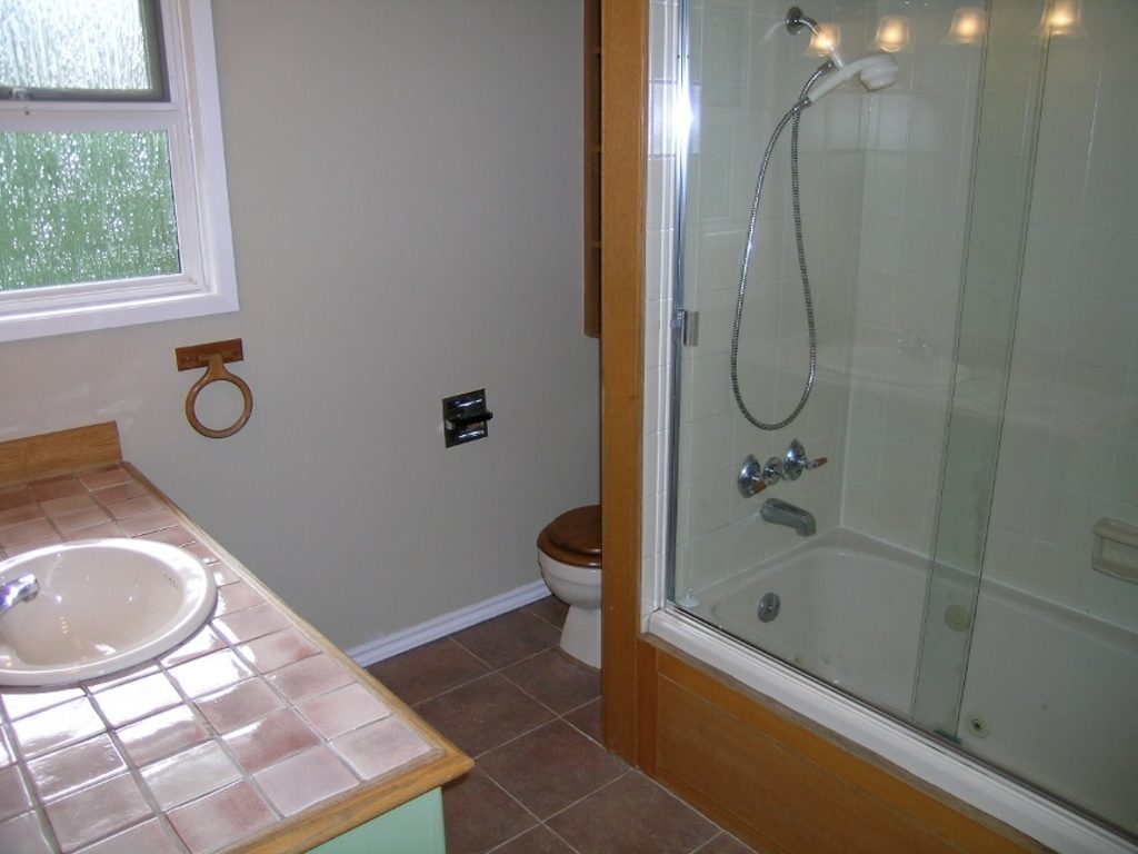Bathroom with wooden vanity, glass shower, and tiled floor. - 2331 Hyannis Drive, North Vancouver