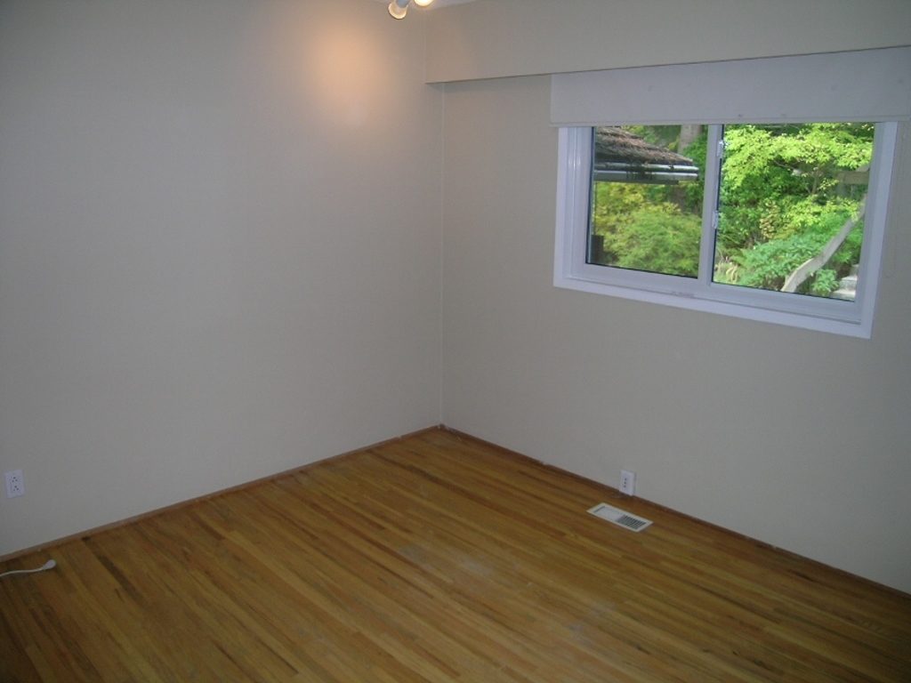Spacious bedroom with hardwood floors and a serene view of greenery outside. - 2331 Hyannis Drive, North Vancouver