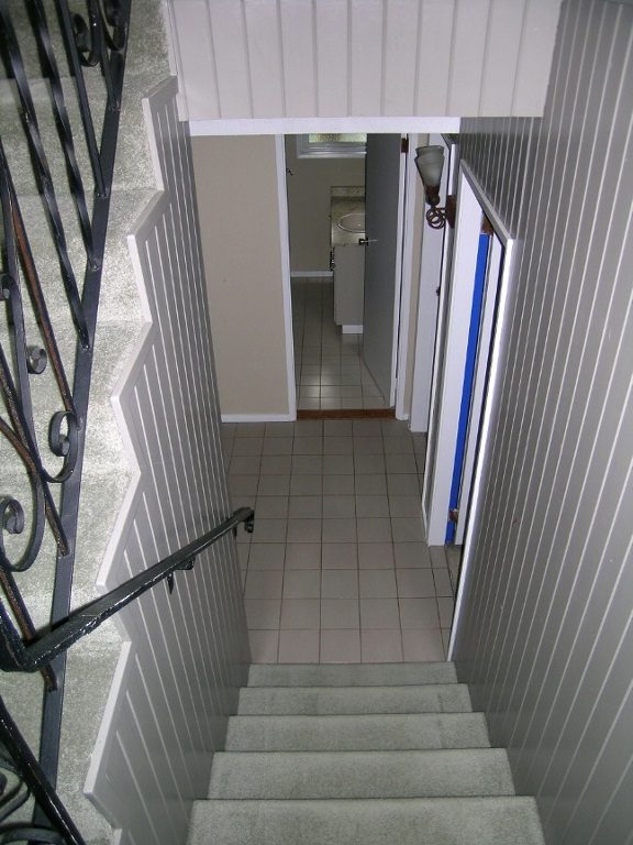 Staircase leading to upper level with tiled walls and black handrails. - 2331 Hyannis Drive, North Vancouver