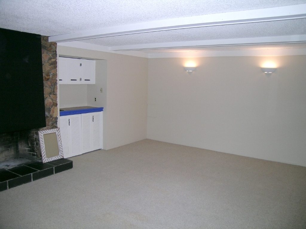 Spacious open-concept living room with white walls, carpeted floors, and a stone fireplace. - 2331 Hyannis Drive, North Vancouver