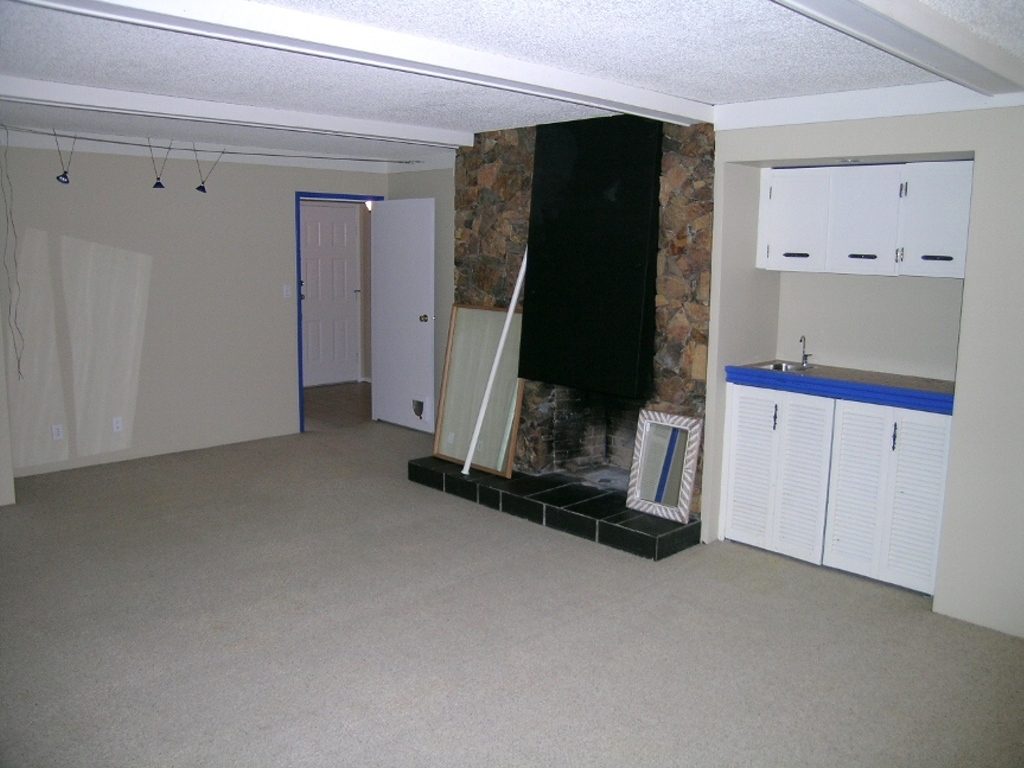 Spacious living room with stone fireplace, white cabinets, and carpeted floors. - 2331 Hyannis Drive, North Vancouver