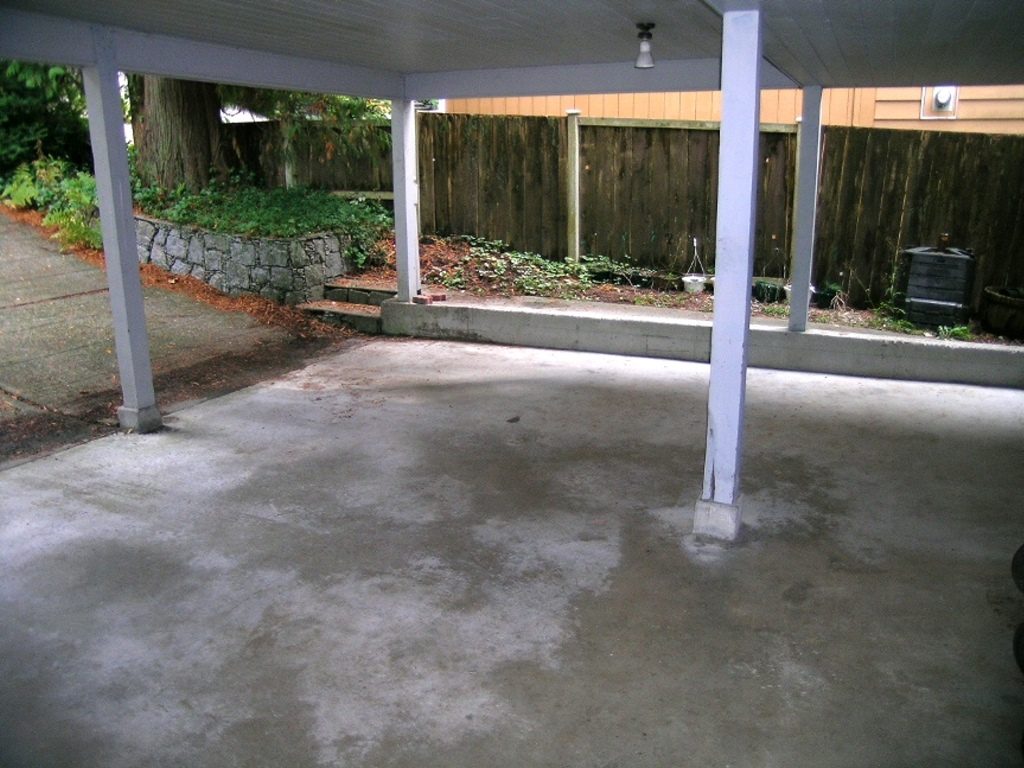 Covered patio with concrete floor and wooden fence backdrop. - 2331 Hyannis Drive, North Vancouver