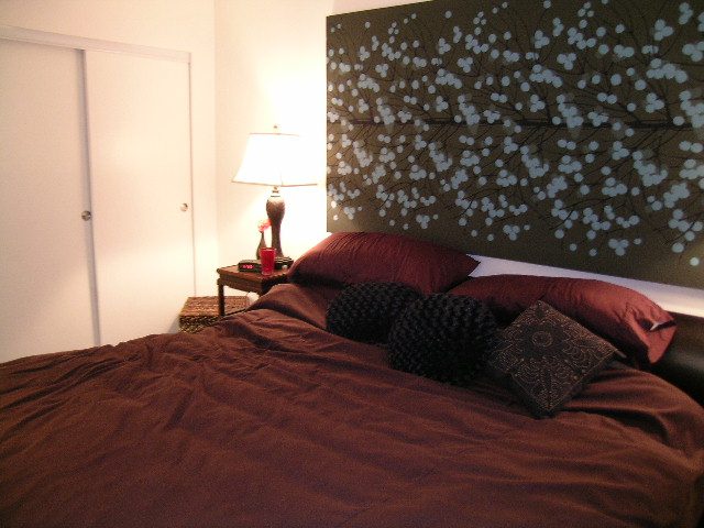 Furnished bedroom with dark bedding, floral artwork, and a bedside lamp. - 930 Beatty Street, Vancouver Downtown