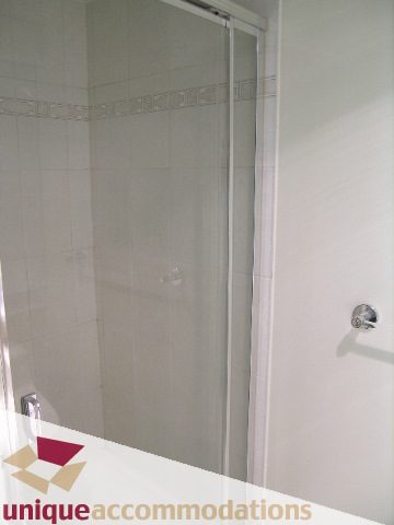 Furnished bathroom with white tiles and a glass shower door. - PH1 - 125 West 2nd Street, North Vancouver