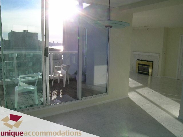 Bright living room with large glass doors, city view, and modern fireplace. - PH1 - 125 West 2nd Street, North Vancouver