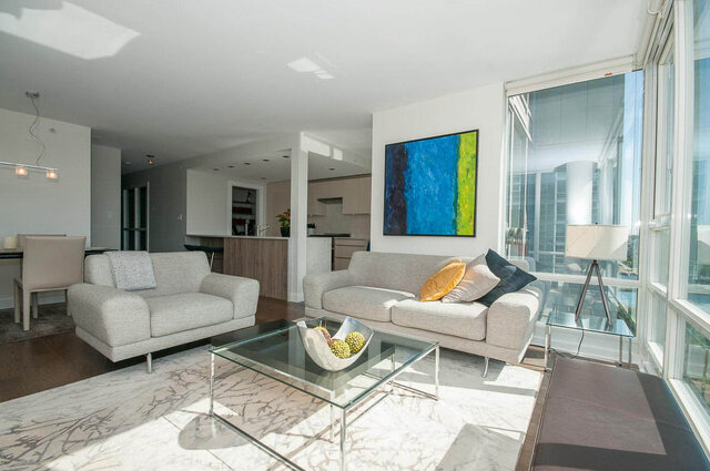 Modern living room with city view and glass coffee table featuring fruit bowl. - 1703-1067 Marinaside Crescent, Vancouver Downtown