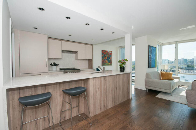 Modern kitchen with marble island and hardwood floors, overlooking city views. - 1703-1067 Marinaside Crescent, Vancouver Downtown