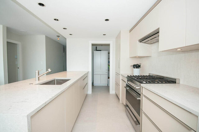 A modern kitchen with white cabinetry, marble countertops, and stainless steel appliances. - 1703-1067 Marinaside Crescent, Vancouver Downtown