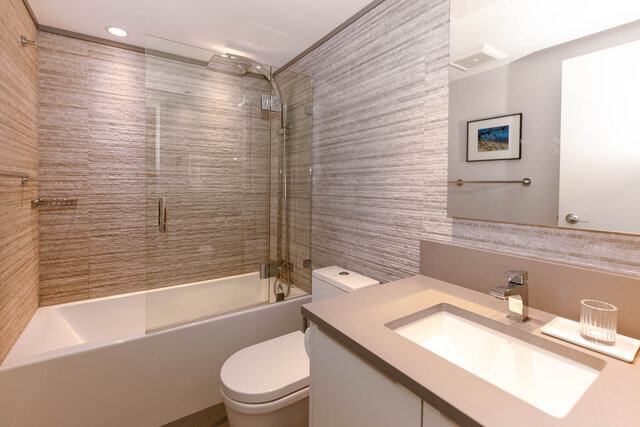 Modern bathroom with integrated sink countertop and glass shower enclosure. - 1703-1067 Marinaside Crescent, Vancouver Downtown
