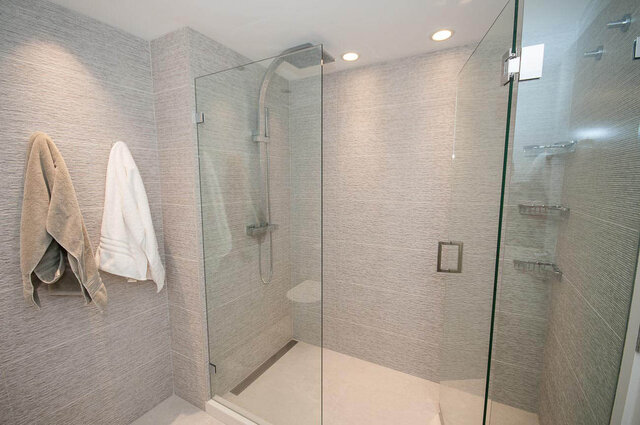 Modern bathroom with glass shower enclosure and textured tile walls. - 1703-1067 Marinaside Crescent, Vancouver Downtown