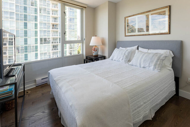 Spacious bedroom with city view and white bedding on hardwood floors. - 1703-1067 Marinaside Crescent, Vancouver Downtown