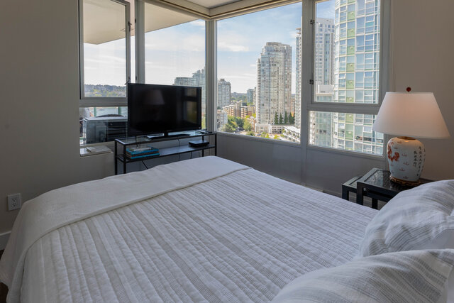 Bedroom with city view and white quilted bed. - 1703-1067 Marinaside Crescent, Vancouver Downtown