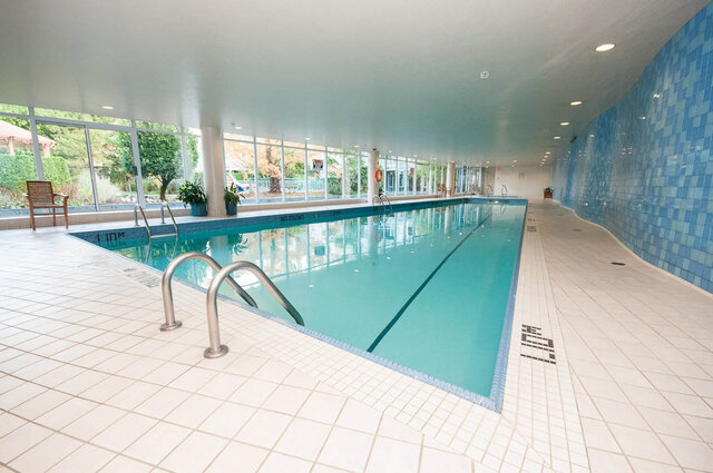 Indoor pool with blue tile walls and greenery view through large windows. - 1703-1067 Marinaside Crescent, Vancouver Downtown