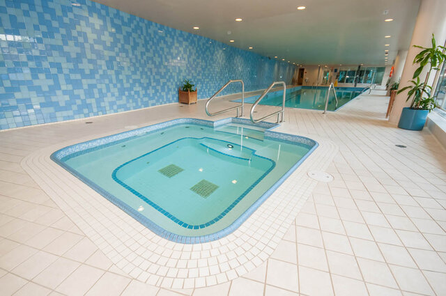 Indoor pool area with blue mosaic tile walls and a hot tub with built-in jets. - 1703-1067 Marinaside Crescent, Vancouver Downtown