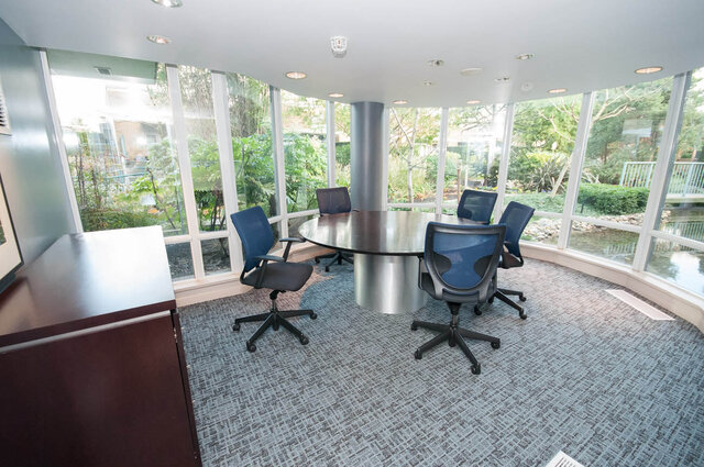 Modern conference room with large round table and garden view through floor-to-ceiling windows. - 1703-1067 Marinaside Crescent, Vancouver Downtown