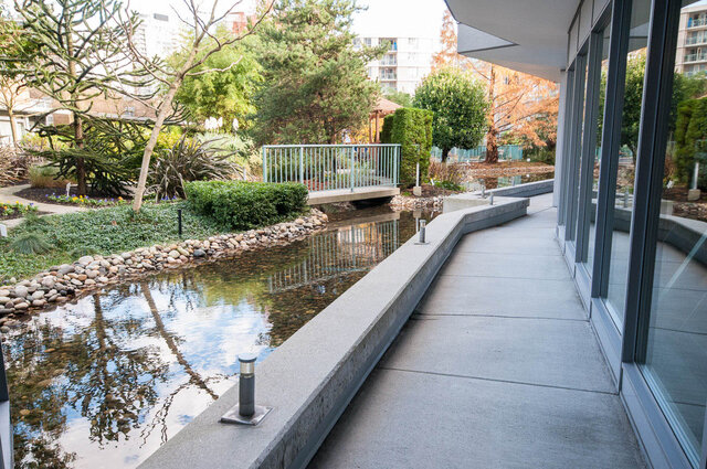 Outdoor patio with serene water feature and lush greenery. - 1703-1067 Marinaside Crescent, Vancouver Downtown