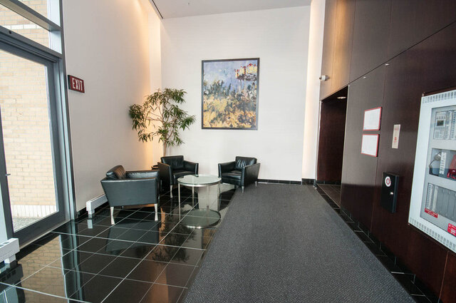Modern lobby with black leather chairs and glass-top table, featuring a large abstract painting. - 1703-1067 Marinaside Crescent, Vancouver Downtown