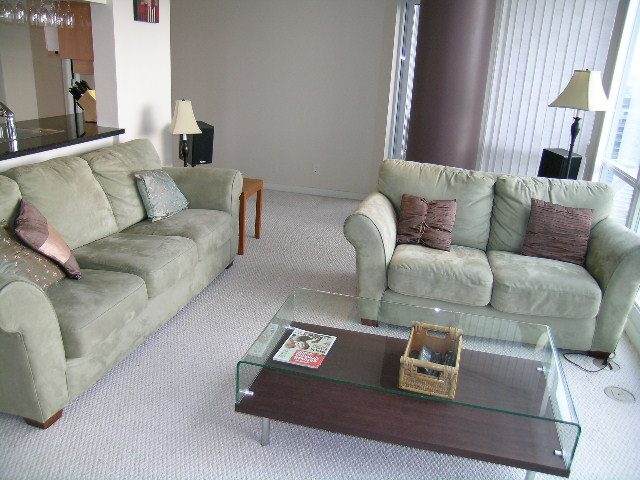 Living room with modern furniture, glass coffee table, and city view. - 1601 - 193 Aquarius Mews, Vancouver Downtown