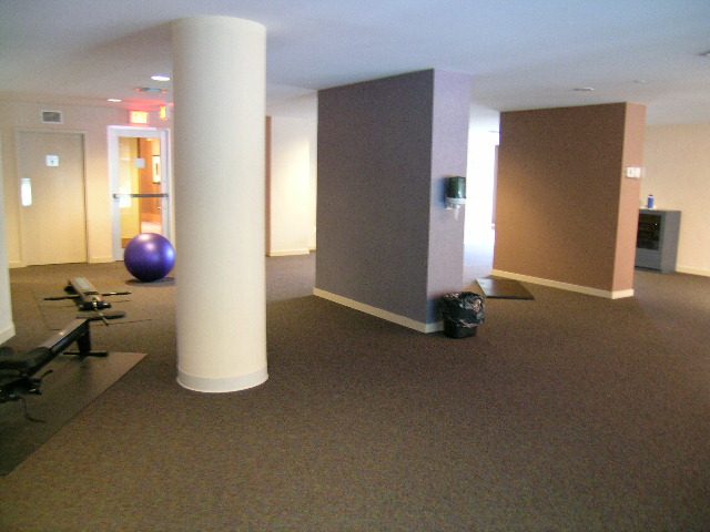 Living room with exercise equipment and large windows. - 1601 - 193 Aquarius Mews, Vancouver Downtown