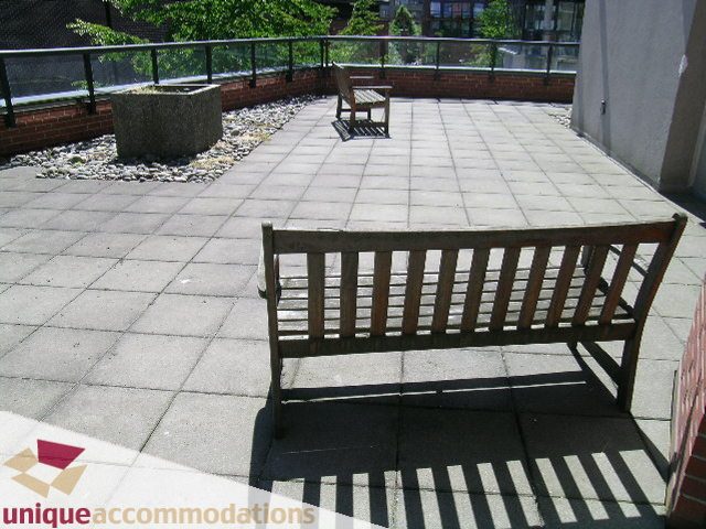Furnished rooftop patio with wooden benches and brick accents. - 11C - 199 Drake Street, Vancouver Downtown