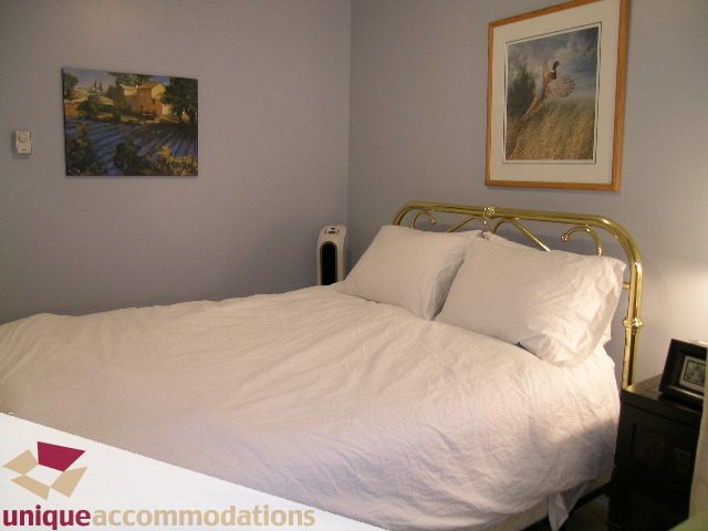 Bright bedroom with white linens, brass headboard, and framed artwork. - 406 - 1688 Cypress Street, Vancouver West Side