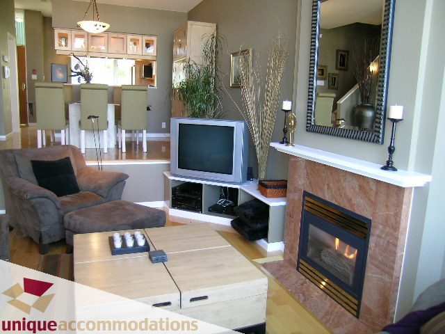 Furnished living room with a cozy fireplace, modern furniture, and a view of the kitchen. - TH 120 - 1228 Marinaside Crescent, Vancouver Downtown
