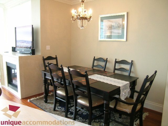 Dining area with dark wood table, six chairs, chandelier, and fireplace. - 1805 - 428 Beach Crescent, Vancouver Downtown