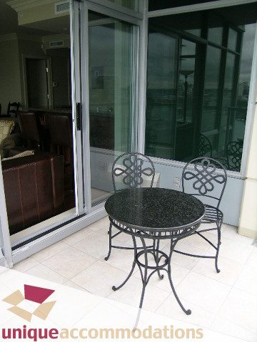 Furnished patio with black glass tables and wrought iron chairs, leading to sliding glass doors. - 1805 - 428 Beach Crescent, Vancouver Downtown