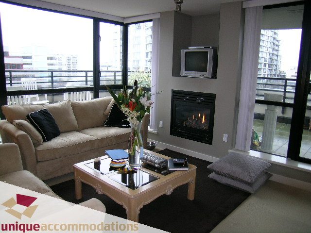Furnished living room with a fireplace, city view, and modern decor. - 305 - 124 West 1st Street, North Vancouver