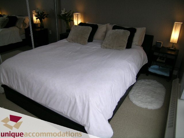 Spacious bedroom with a king-sized bed, plush pillows, and soft lighting. - 305 - 124 West 1st Street, North Vancouver