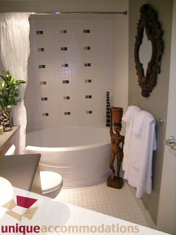 Bright bathroom with white mosaic tiles and a round tub, featuring a wooden mirror and a potted plant. - 305 - 124 West 1st Street, North Vancouver