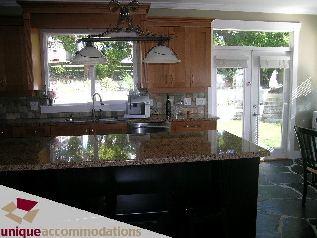Bright kitchen with granite countertops and hardwood floors, featuring a large window with a view of the outdoors.
