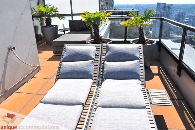 Furnished rooftop lounge with city view, lounge chairs, and potted plants. - PH1 - 969 Richards Street, Vancouver Downtown