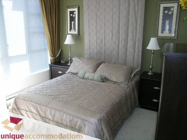 Spacious bedroom with quilted bedding, nightstands, and lamps. - 945 Homer Street, Vancouver Downtown
