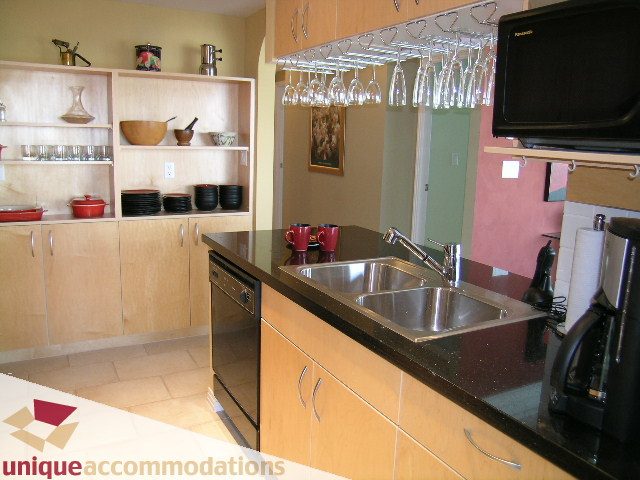 Bright kitchen with granite countertops, modern appliances, and wine glass rack. - 2502 - 1199 Marinaside Crescent, Vancouver Downtown