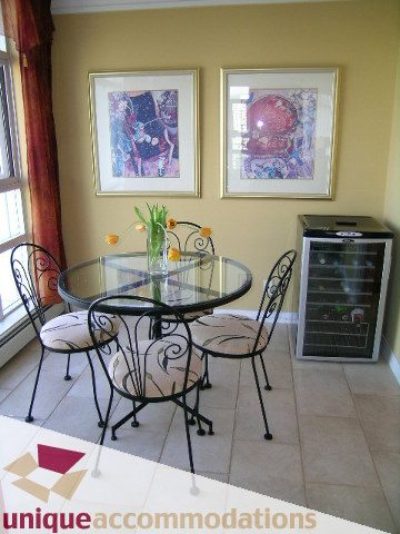Furnished dining area with glass table, wrought iron chairs, and framed artwork on yellow walls. - 2502 - 1199 Marinaside Crescent, Vancouver Downtown
