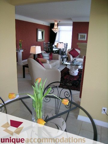 Furnished living room with red walls, modern furniture, and a chandelier. - 2502 - 1199 Marinaside Crescent, Vancouver Downtown