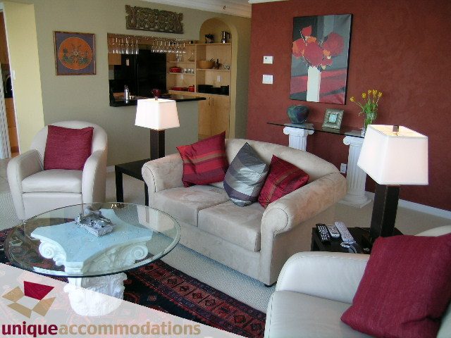 Bright living room with glass coffee table, red and beige furniture, and artwork on the walls. - 2502 - 1199 Marinaside Crescent, Vancouver Downtown