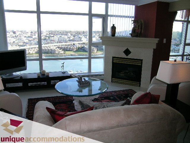 Furnished living room with a city view, modern fireplace, and glass coffee table. - 2502 - 1199 Marinaside Crescent, Vancouver Downtown