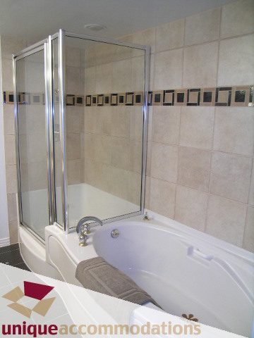 Furnished bathroom with a corner bathtub and glass shower enclosure. - 2502 - 1199 Marinaside Crescent, Vancouver Downtown