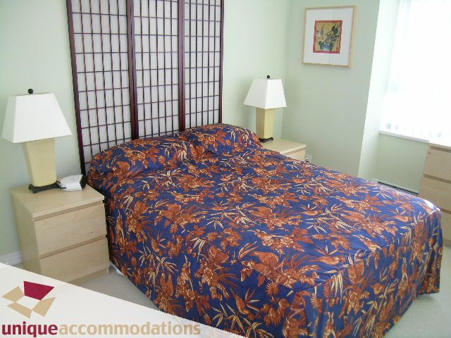 Furnished bedroom with floral bedding, nightstands, and lamps. - 2502 - 1199 Marinaside Crescent, Vancouver Downtown