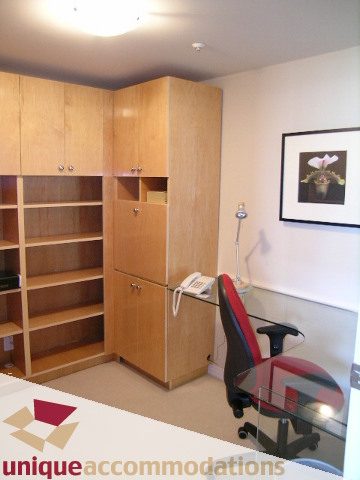 Furnished den with built-in shelves and desk, modern office chair, framed artwork. - 2502 - 1199 Marinaside Crescent, Vancouver Downtown