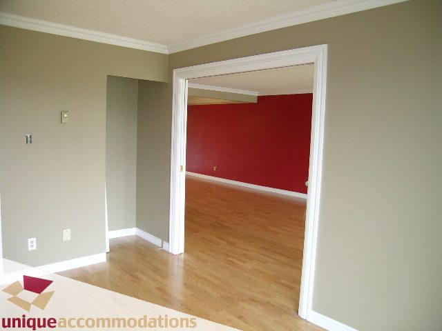 Furnished 1-bedroom + den with hardwood floors and a red accent wall. - 105 - 1490 Pennyfarthing, Vancouver West Side