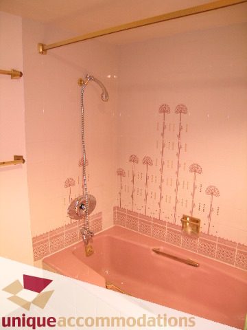 Furnished bathroom with pink bathtub and shower, wallpapered walls. - 105 - 1490 Pennyfarthing, Vancouver West Side